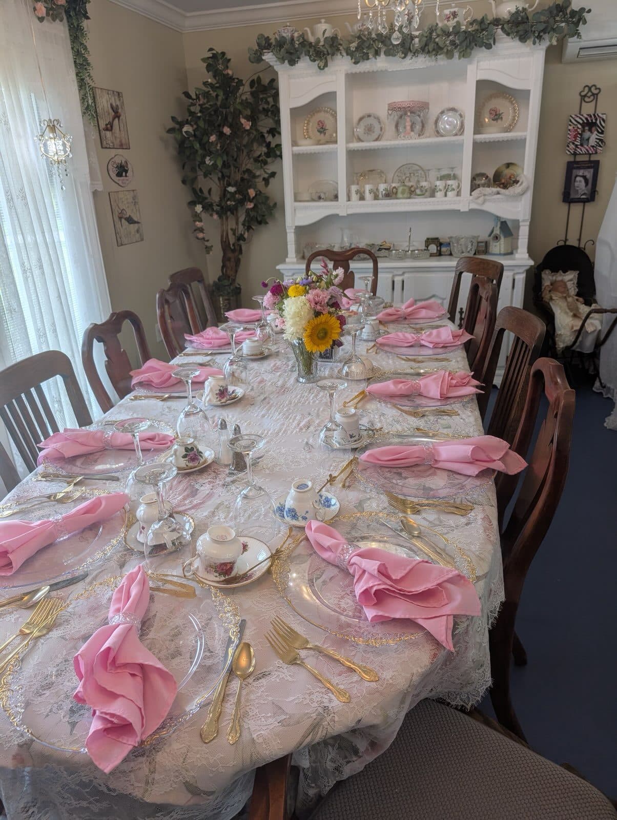 The long table set with lace, crystal, gold flatware and pink napkins