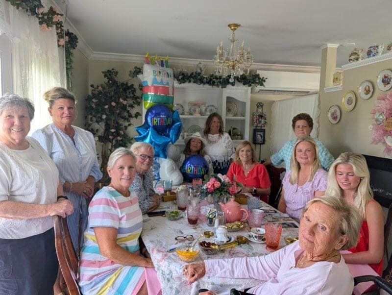 A birthday party around the long table, balloons behind