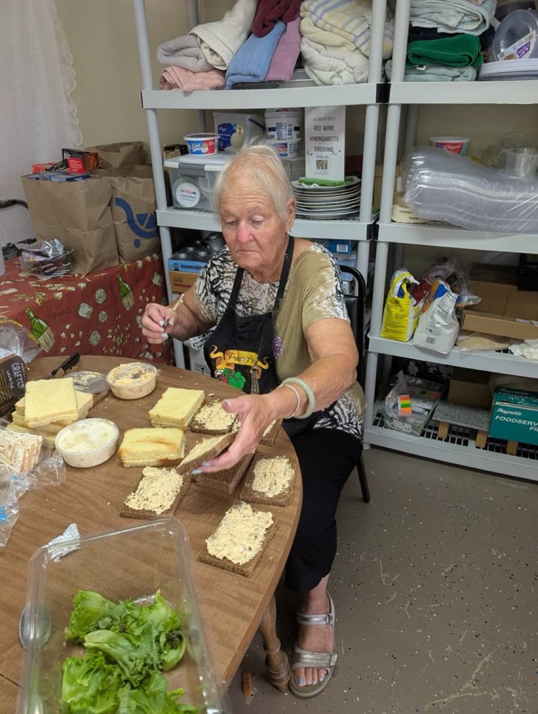 Ginny in her apron building sandwiches at the prep table