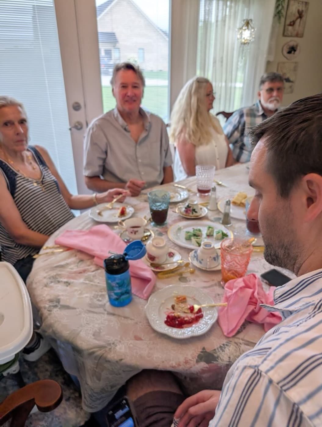 Guests at the bright window end of the room, dessert plates on the table