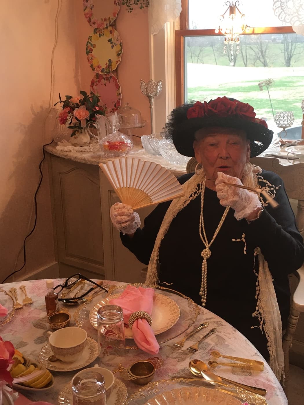 Ruth King raising a folded fan at the laid table